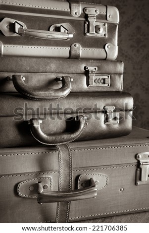 Pile of leather vintage suitcases, retro wallpaper on background.