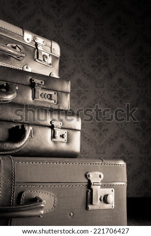 Pile of leather vintage suitcases, vintage wallpaper on background.