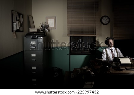1950s style reporter working late at night sitting at his desk.