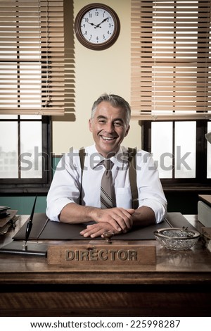 Cheerful director sitting at office desk, 1950s vintage office.