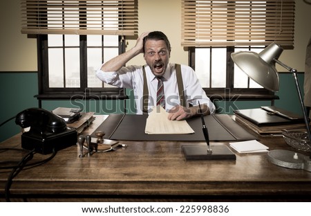 Shocked vintage businessman with mouth open working at desk and checking paperwork.