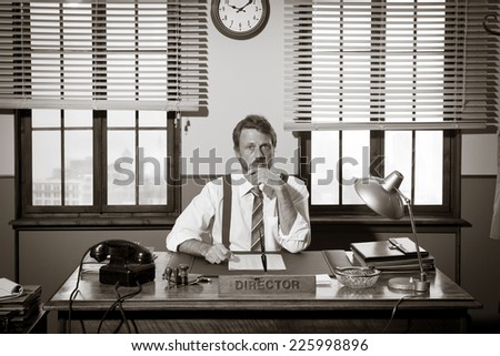 Vintage director working at office desk and looking at camera.