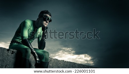 Pensive superhero with hand on chin and dramatic cloudy sky on background.