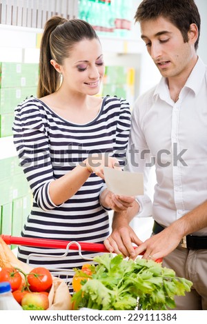 Attractive couple shopping at supermarket with shopping list.