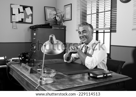 Cheerful director sitting at office desk, 1950s vintage office.