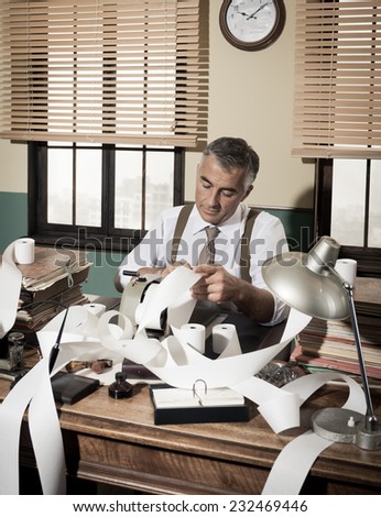 Busy vintage accountant with adding machine surrounded by cash register tape.