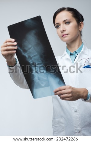 Confident female radiologist checking x-ray image of spinal column.