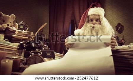 Santa Claus reading a very long Christmas list and looking at camera.