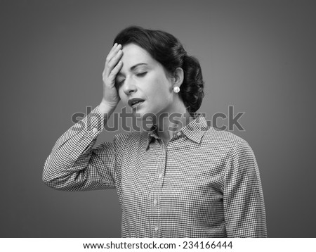 Tired 1950s style woman touching her foehead with mouth open