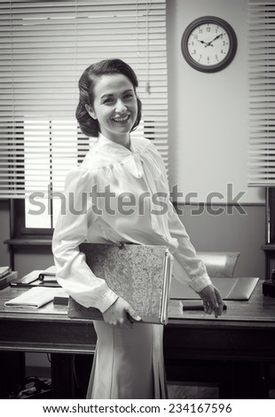 Cute vintage secretary working at office, smiling and holding a folder with paperwork