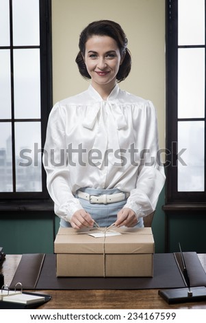 Smiling vintage secretary holding a mail package with rope and label
