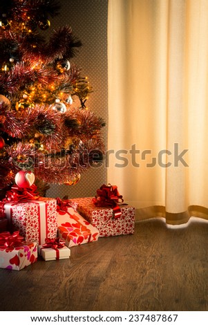 Colorful christmas tree with red and white gift boxes on elegant hardwood floor.