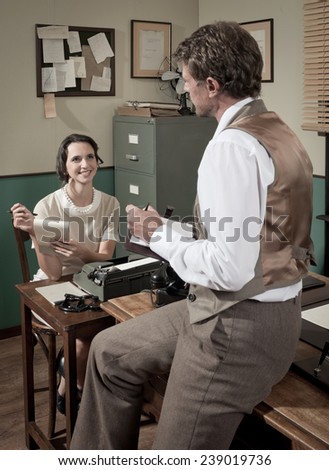 Vintage director and female secretary working together in 1950s style office.