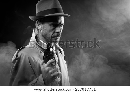 Handsome detective in trench coat holding a gun in the dark, film noir
