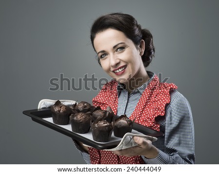Smiling vintage woman holding a baking tray with chocolate home made muffins