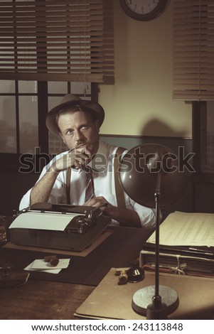Retro writer working at desk with a typewriter looking for inspiration.