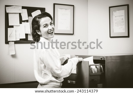 Smiling vintage secretary searching files in the filing cabinet open drawers