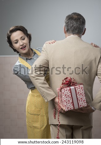 Vintage romantic couple at home, he is giving to his wife a beautiful surprise gift
