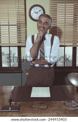 Attractive  businessman with hand on chin smiling at camera, vintage office.