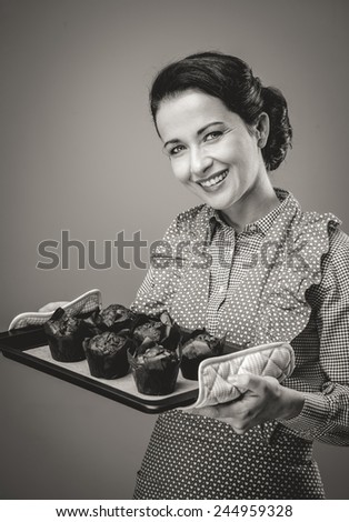 Smiling vintage woman holding a baking tray with chocolate home made muffins