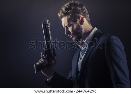 Brave cool man holding a dangerous weapon on dark background