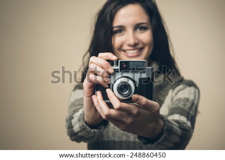 Young attractive woman smiling and holding a vintage camera