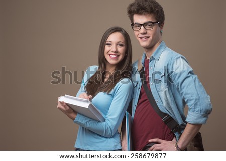 Happy teenager students holding textbooks and smiling