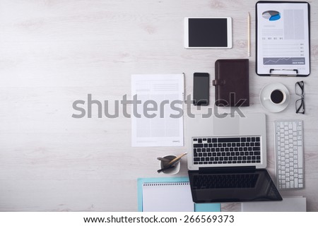 Businessman tidy desktop with laptop, tablet, smartphone, financial reports and various objects, copyspace on the left, top view