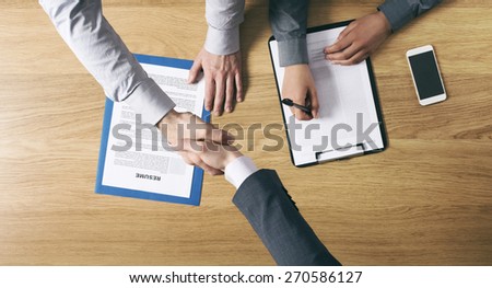 Employer hiring and giving an handshake to the candidate after the job interview, hands close up top view