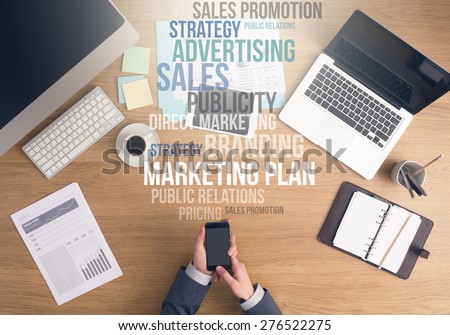 Businessman working at office desk, hands using a smart phone top view, marketing and business text concepts above desktop