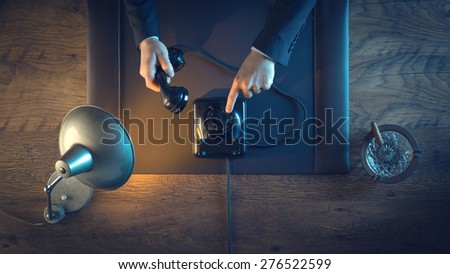 Vintage business man holding the phone receiver, dialing a number and phone calling, top view