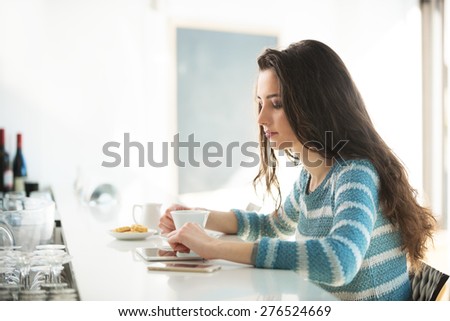 Beautiful girl leaning at the bar counter and using a digital tablet