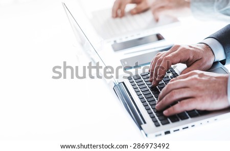 Professional businessmen working on laptops at office desk, hands close up, unrecognizable people