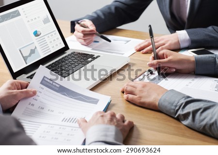 Business professionals working together at office desk, hands close up pointing out financial data on a report, teamwork concept