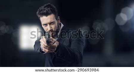 Cool aggressive man in shirt and jacket pointing a gun