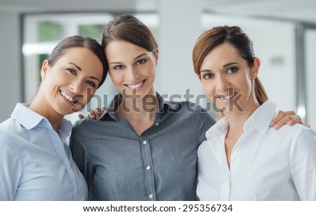 Business women posing together in the office and smiling at camera, teamwork and women empowerment concept