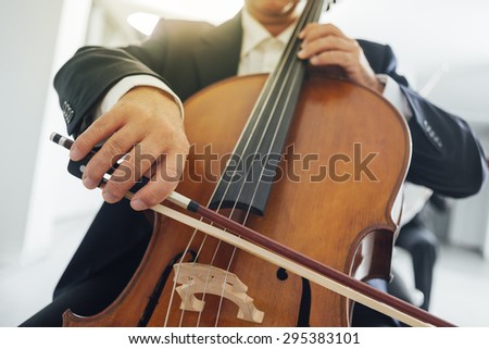Professional cello player\'s hands close up, unrecognizable person