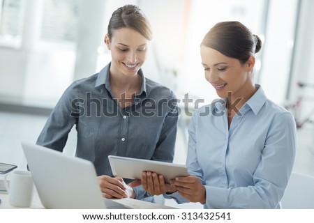 Professional business women working together at office desk and using a touch screen tablet