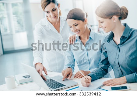 Smiling business women team working at office desk and discussing a project on a laptop