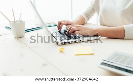 Woman sitting at desk and working at computer hands close up