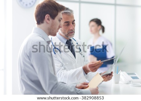 Doctor examining an x-ray and pointing, the patient is listening and watching, healthcare concept