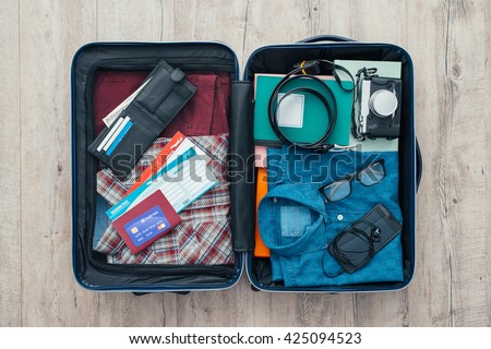 Open traveler\'s bag with clothing, accessories, credit card, tickets and passport, travel and vacations concept