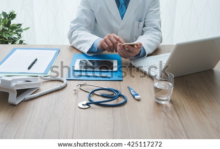 Professional doctor working at office desk, he is using a smartphone, healthcare and technology concept