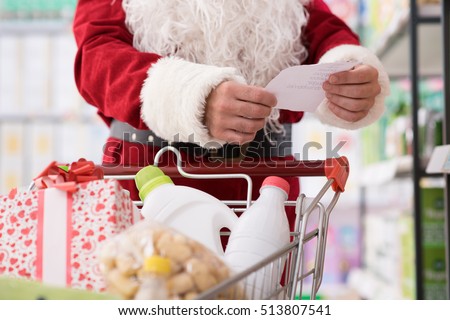 Santa Claus doing grocery shopping at the supermarket, he is pushing a full cart and checking a list, Christmas and shopping concept