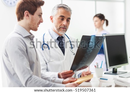 Doctor in the office examining an x-ray and discussing with a patient