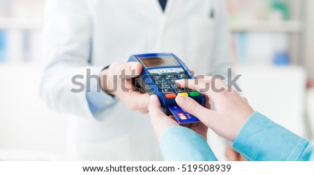 Woman shopping at the pharmacy with a credit card and entering a security pin on the terminal, hands close up