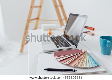 Home makeover, renovation and decoration: laptop on a desktop with color swatches and paint rollers