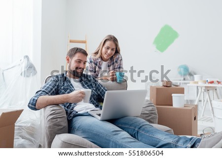 Couple relaxing during home renovation, they are connecting with a laptop and having a coffee break