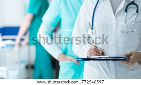 Medical staff working at the hospital: doctor and nurse checking a patient\'s medical record on a clipboard, healthcare and medical exams concept