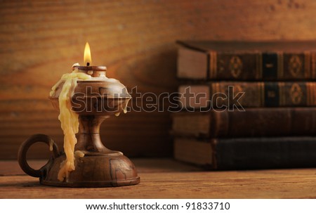 old candle on a wooden table, old books in the background, similar photo in my portfolio
